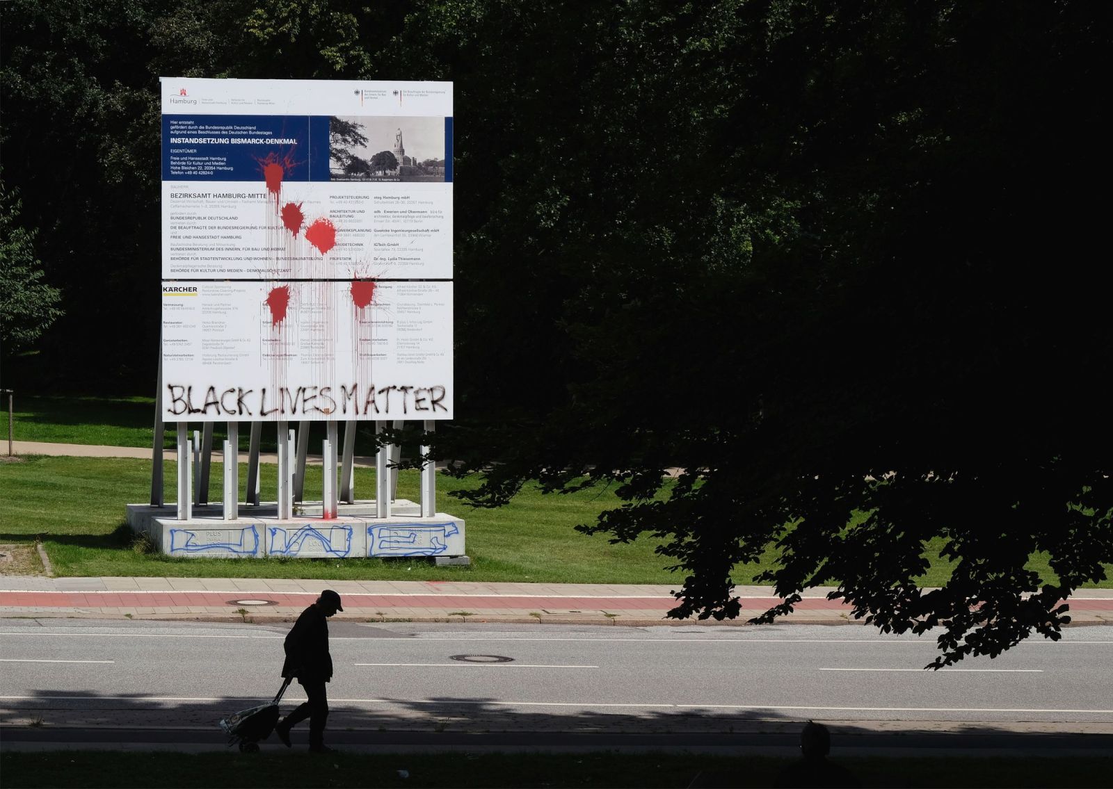 Painel informativo da intervenção de restauro, 2020. No seguimento do movimento Black Lives Matter, diversos monumentos de cariz colonial existentes em Hamburgo foram alvo de ataques com sacos de tinta vermelha. Em sinal de protesto contra a irrefletida restauração do Monumento a Bismarck em Hamburgo, também contra o painel informativo da intervenção foi lançada tinta vermelha, sendo este ainda grafitado com as palavras de ordem do movimento BLM. Foto: © afrika-hamburg.de
